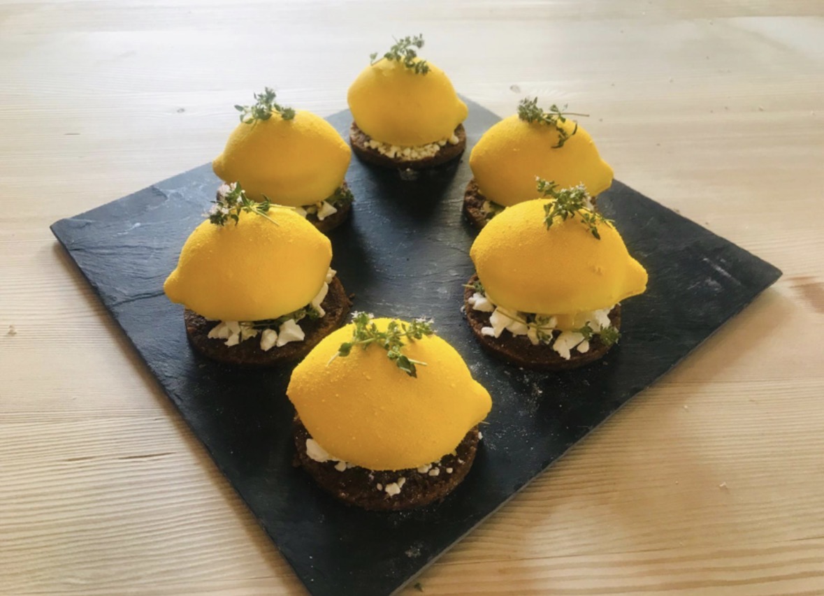 Lemon mousse desserts on chocolate sponge, served on slate