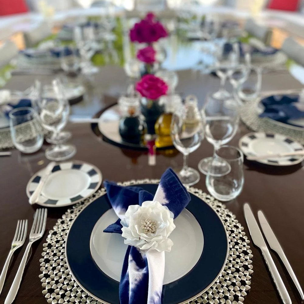 A table laid with navy linen, glassware and flowers ready for guests to arrive